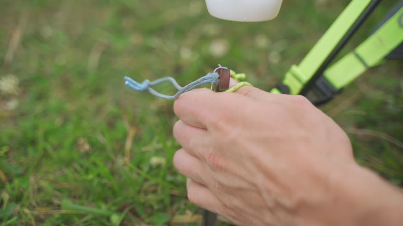 vista estática en cámara lenta de un joven que usa un martillo para golpear las estacas de la tienda en hierba verde brillante mientras acampa de vacaciones en un bosque en pensilvania