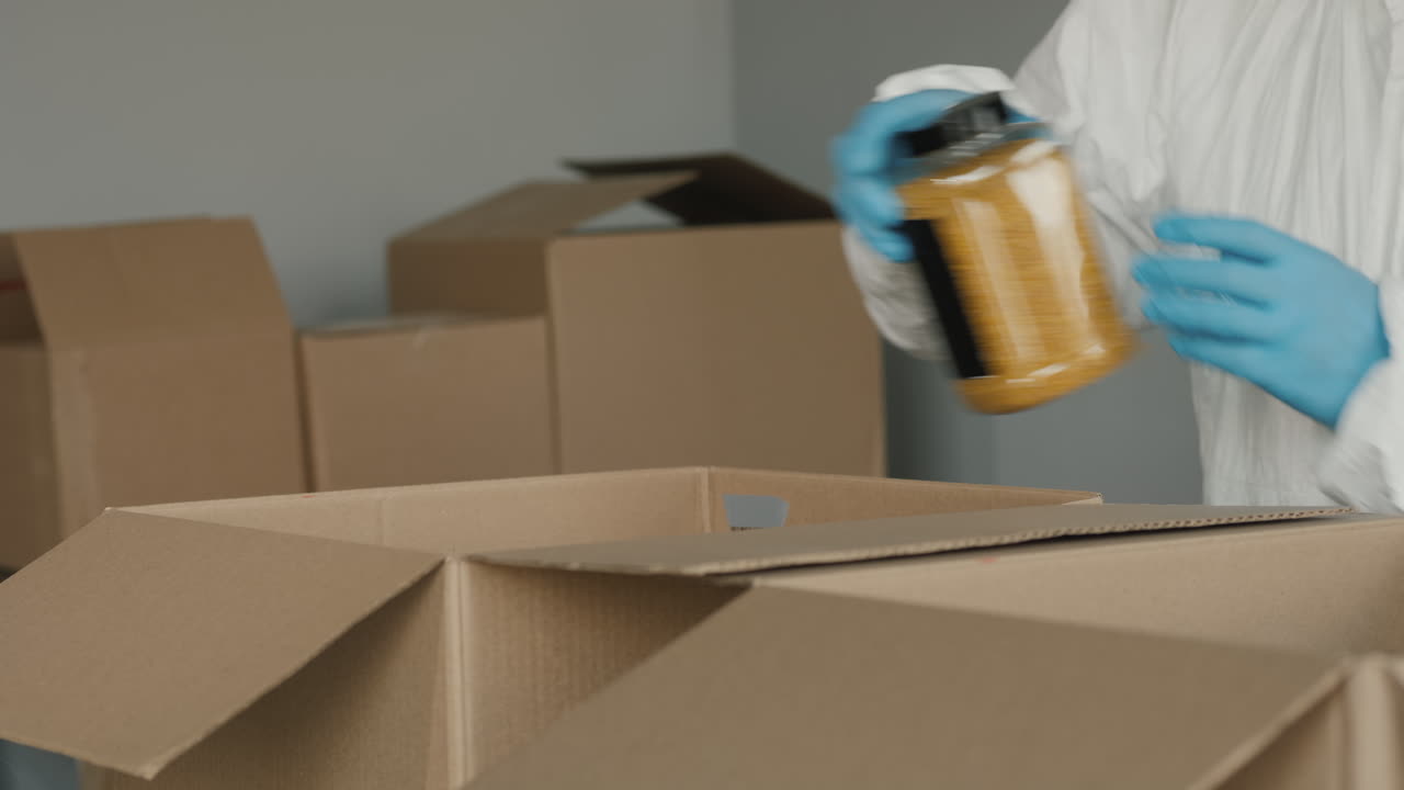 보호복과 장갑을 낀 남자가 상자에 음식을 포장합니다.