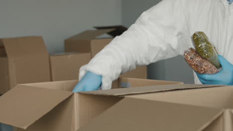 a man in a protective suit and gloves packs food in boxes