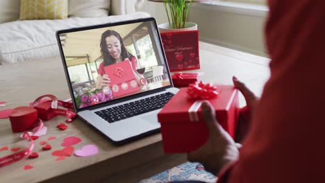 Glückliche-Biraziale-Frau-Mit-Vitiligo,-Die-Ein-Geschenk-öffnet-Und-Einen-Valentinstag-Videoanruf-Auf-Dem-Laptop-Macht