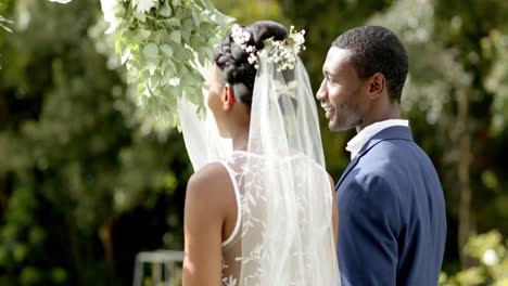 Feliz-Pareja-Afroamericana-Sonriendo-En-Su-Ceremonia-De-Boda-En-Un-Jardín-Soleado,-En-Cámara-Lenta