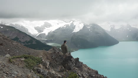 hombre en una montaña escarpada admirando la pintoresca vista del lago garibaldi en el parque provincial garibaldi, bc, canadá