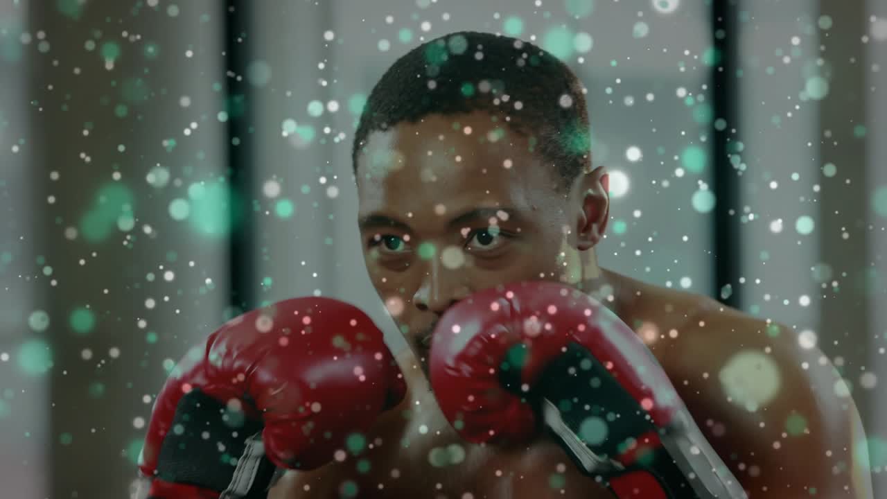 Male boxer fixing gaze, lifting red gloves, throwing punches for boxing, particle drifting over him