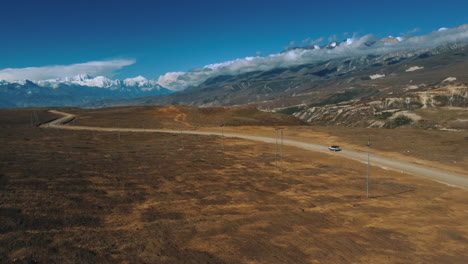 Un-Jeep-Escorpio-Se-Desliza-A-Través-Del-Desierto-Montañoso-De-Nepal-Mustang,-Rodeado-De-Impresionantes-Estructuras-Naturales-Y-Majestuosos-Picos,-Creando-Un-Paisaje-Impresionante