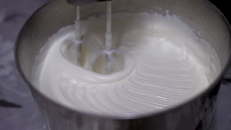 cream being whisked in metal tin by machine on kitchen table