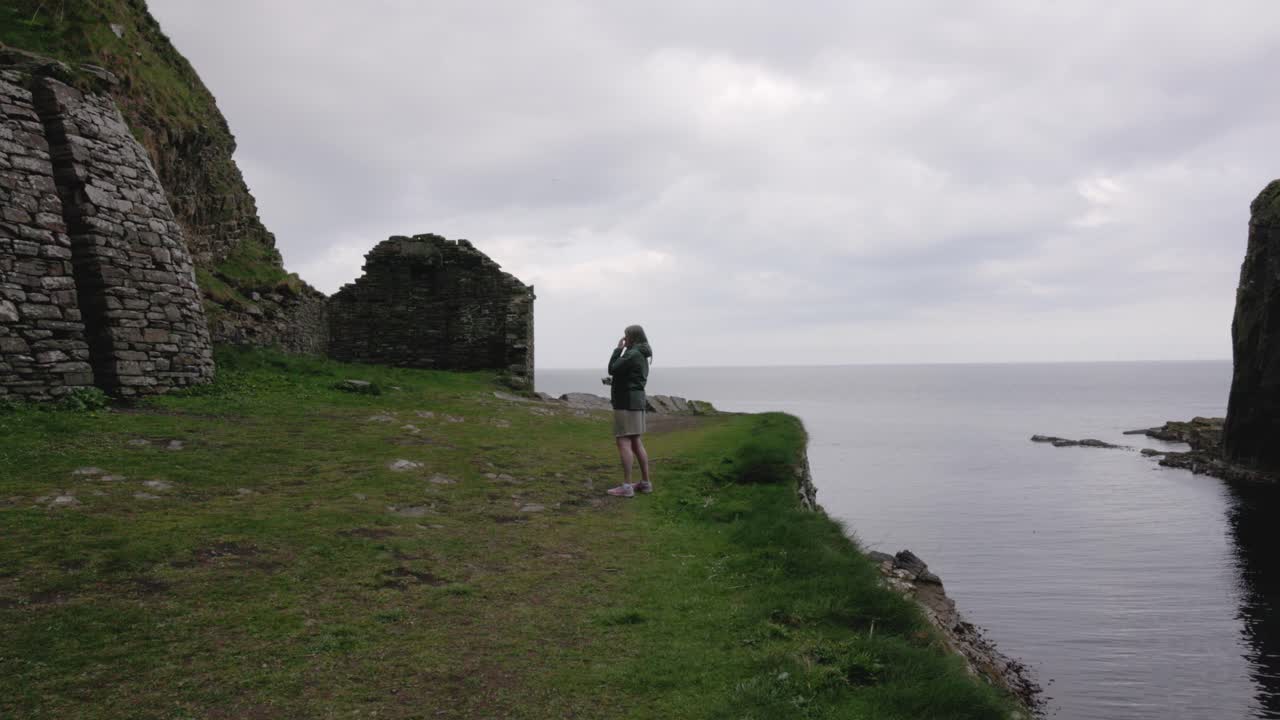 female tourist taking photos of the beautiful Whaligoe Stone Steps at the NC500