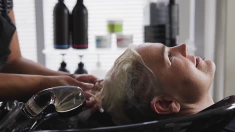 side view woman having her hair washed by a hairdresser