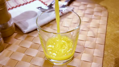 Jugo-De-Naranja-Vertido-En-Un-Vaso,-El-Desayuno-De-La-Mañana.-Cámara-Lenta-Con-Seguimiento-De-Rotación.