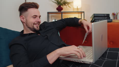 young guy using credit bank card and laptop, transferring money, purchases online shopping