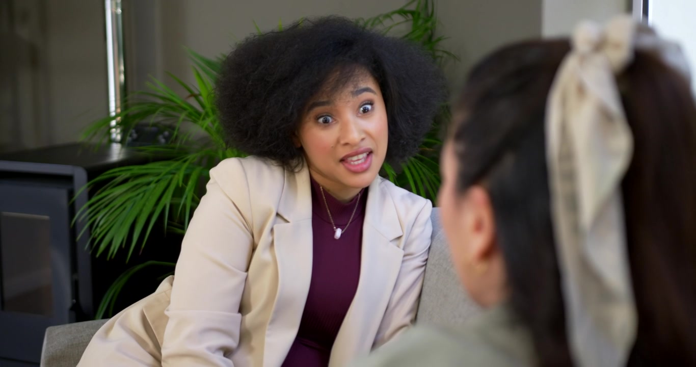 Donna afroamericana con le mani giunte, che si china, condivide durante una riunione con un blazer, ascoltatrice asiatica