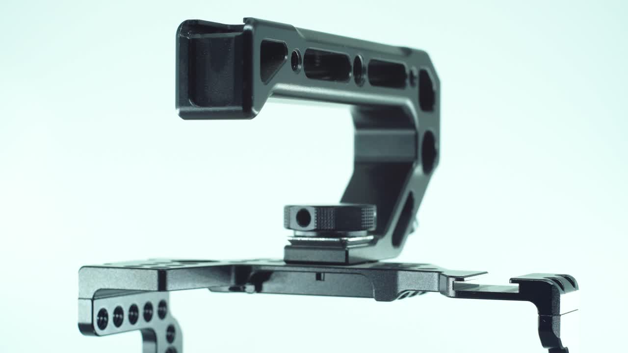 un primer plano de una jaula de cámara de metal negro con un controlador arriba, equipo de producción de video, en un soporte giratorio 360, luz de estudio, cámara lenta, 4k