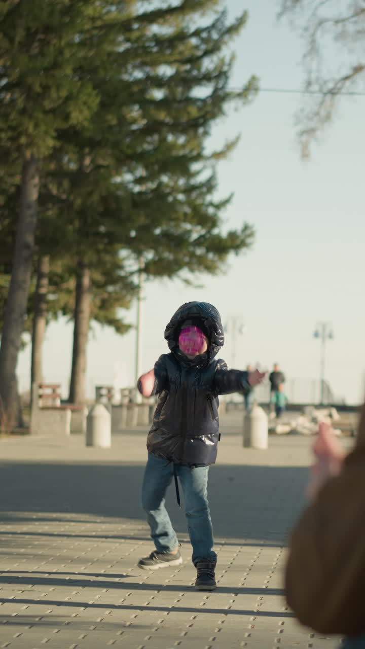 야외에서 놀고 있는 아버지와 아들의 클로즈업, 아이가 보라색 날아다니는 장난감을 공중으로 내보내면서 아버지가 그것을 잡기 위해 서두르며, 배경에는 사람들이 고 있다.