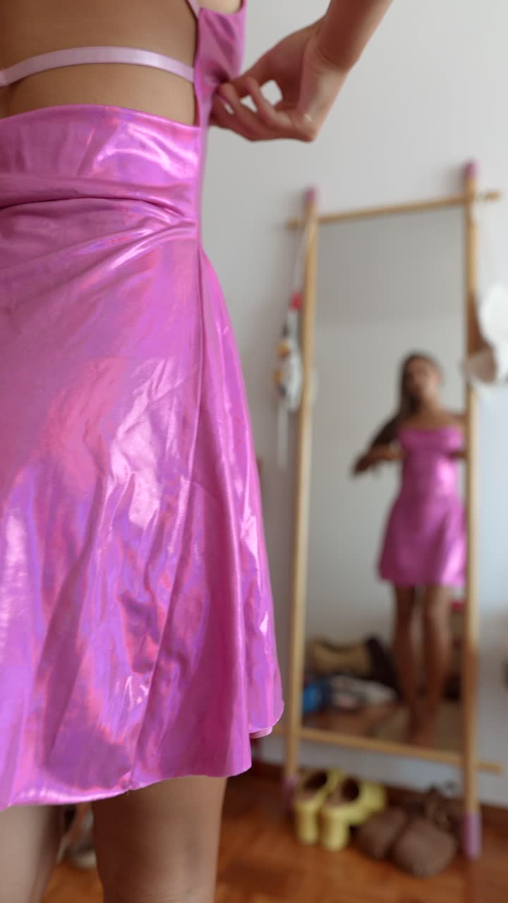 Woman in pink metallic dress reflecting in mirror