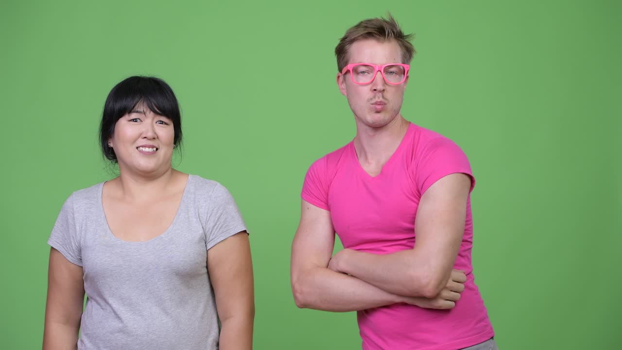Happy overweight Asian woman and young gay man smiling together