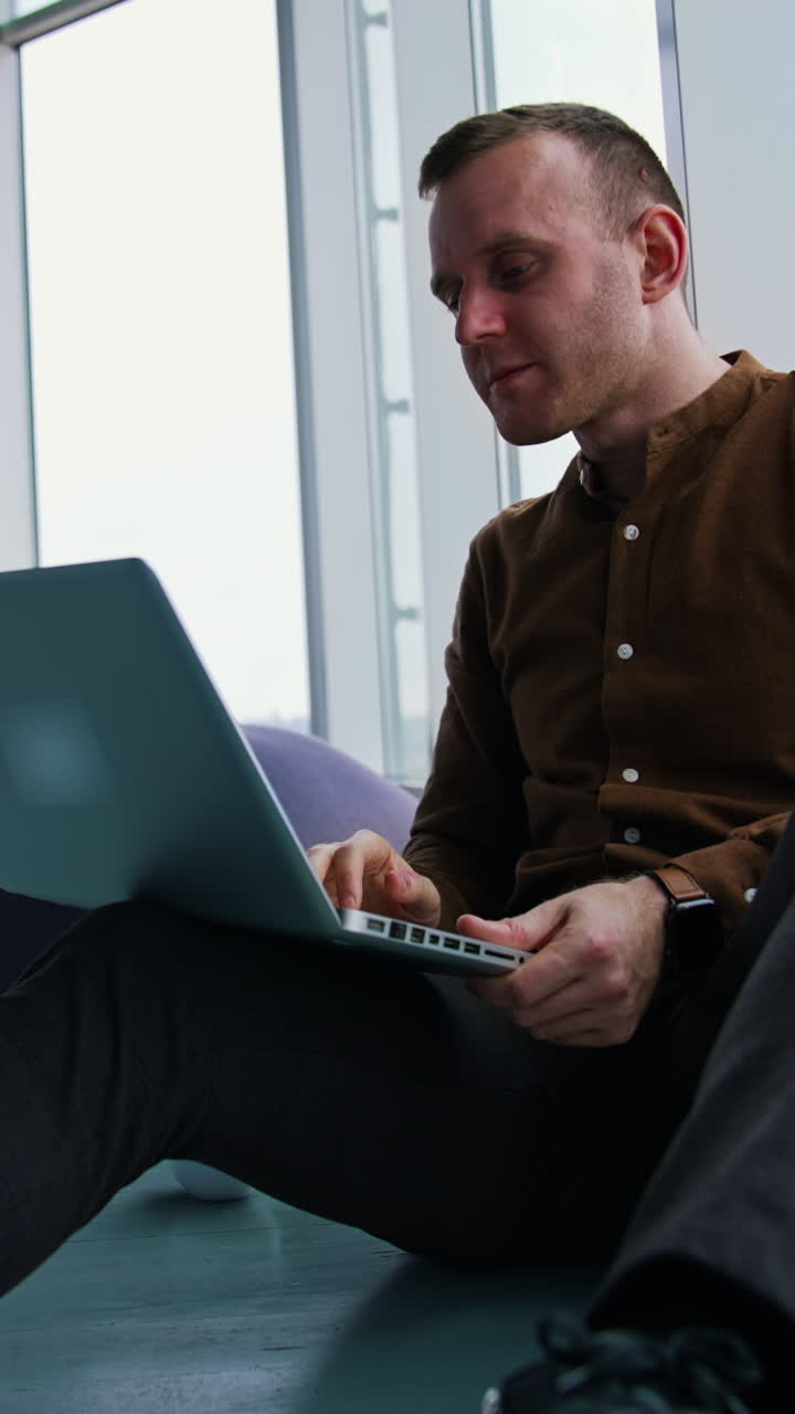 young man sitting on a floor with laptop computer. Work stress concept of man Vertical video