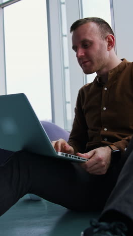young man sitting on a floor with laptop computer. work stress concept of man vertical video