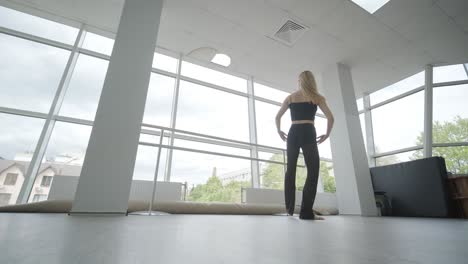 chica en forma con ropa negra actuando contemporáneamente. bailarina muestra movimientos fluidos, cuerpo y manos ondas en la habitación blanca. coreografía de danza de ballet moderno. joven se mueve suavemente