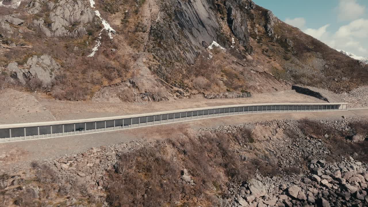 Car Driving On The Road With Rock Shed In Summer In Reine, Moskenes, Nordland, Norway. - aerial shot