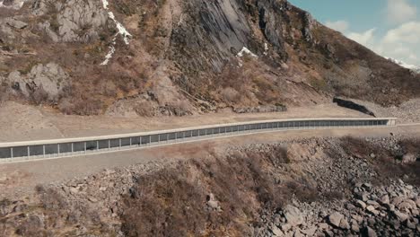 car driving on the road with rock shed in summer in reine, moskenes, nordland, norway. - aerial shot