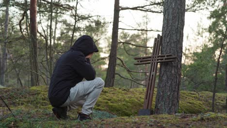 man kneeling and crying in front of a wooden cross