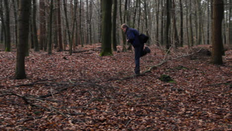 man with photo camera hiking through forest in autumn