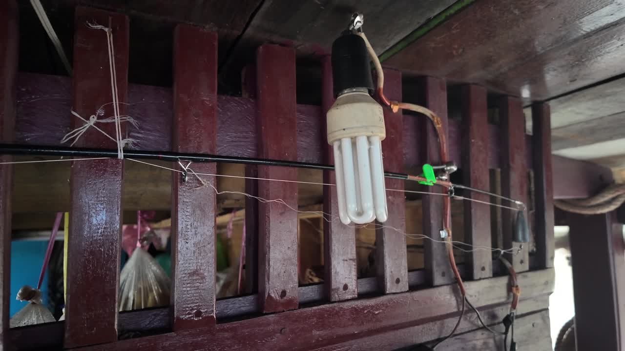 Sebuah bohlam lampu neon tergantung dari struktur kayu di atas perahu yang bergerak perlahan di Laos, Asia Tenggara