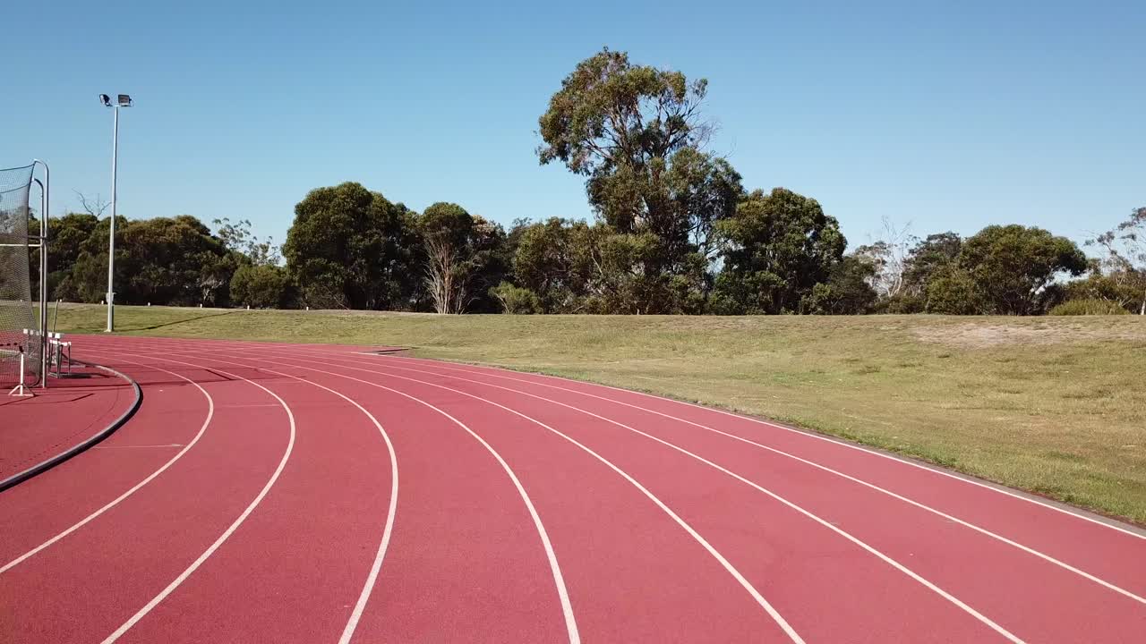 perspectiva en primera persona corriendo alrededor de la primera esquina de una pista de goma roja de atletismo