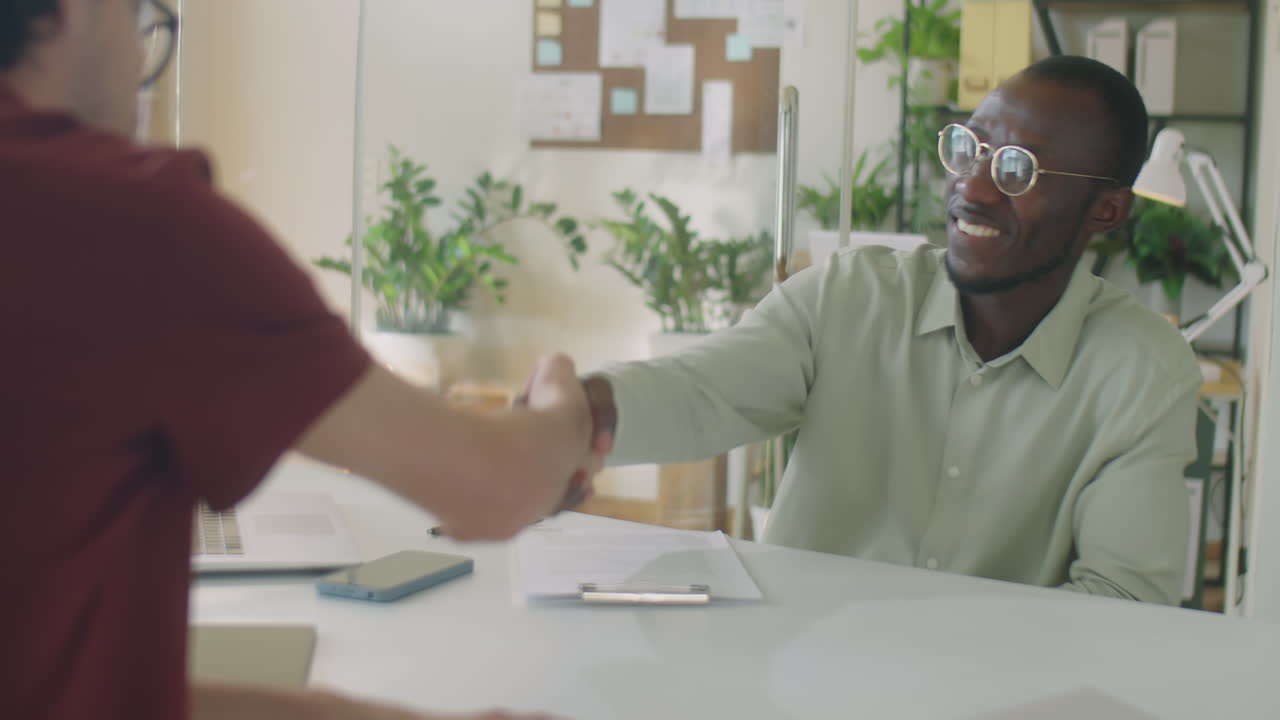 Black Businessman Signing Contract and Shaking Hands with Colleague