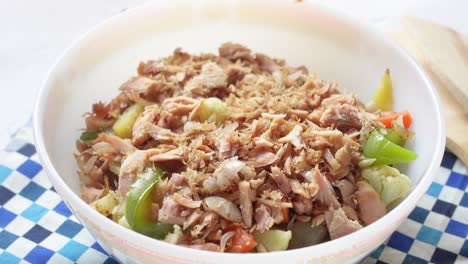 Spoon-pick-tuna-salad-from-a-bowl-on-table