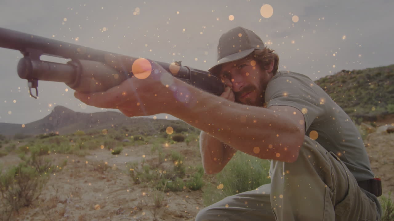 Man crouching with rifle in desert landscape, showing technology overlay and golden sparkles