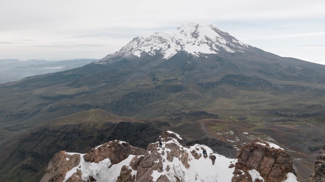 Alpinisti sulla cima del Vulcano Carihuairazo con il Vulcano Chimborazo sullo sfondo
