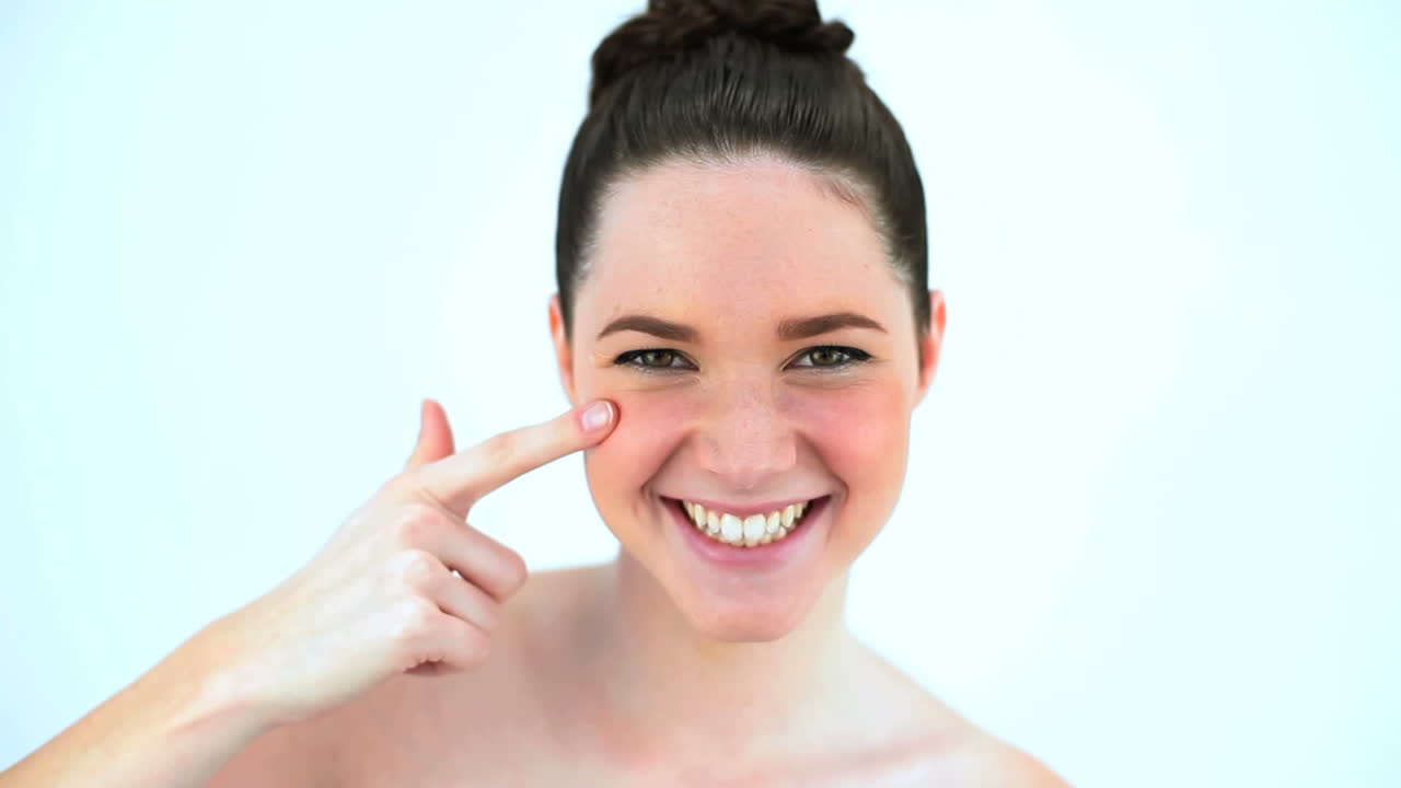 mujer morena extendiendo crema de belleza en su mejilla