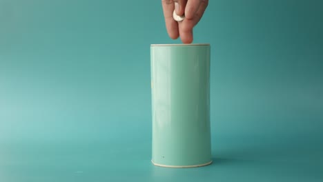 hand filling a teal cylindrical container