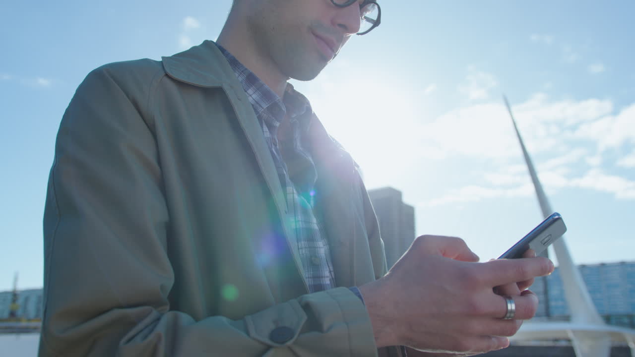 Young Man Typing Message on Phone Outdoors in the City
