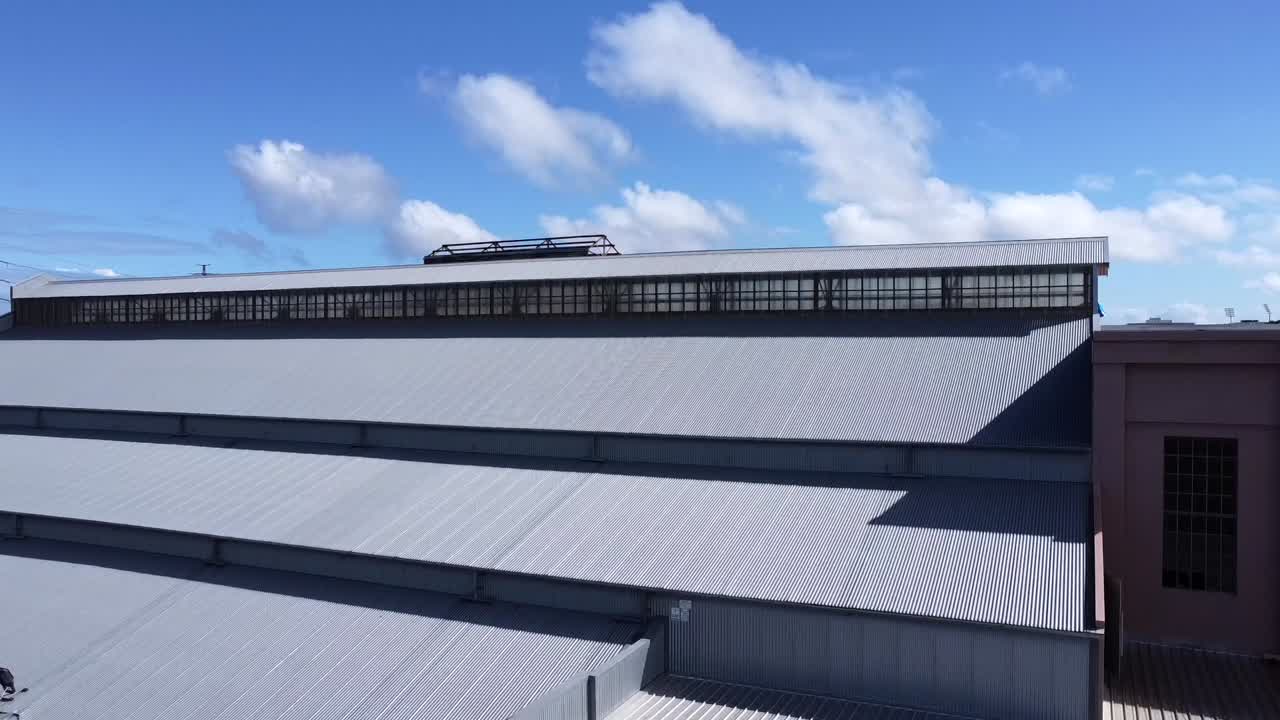 спускаясь с горизонта на крышу заброшенной, неиспользуемой, заброшенной ар-деко электростанции складской фабрики в восточном перте с длинными окнами ар-деко и птицами, летающими мимо