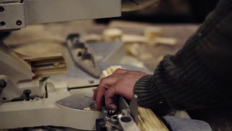 the craftman is working on electric saw machine. sawing a large wooden bar. man cut accurate one pieace for work. slow motion