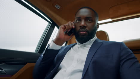 afro business man talking on mobile phone in luxury car