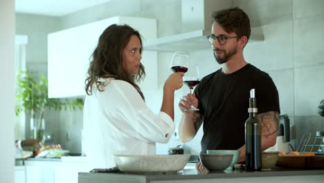 happy young couple drinking red wine at kitchen