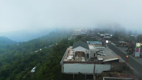 drone flying up high in the clouds above the mountain road on the edge of a cliff in north of bali