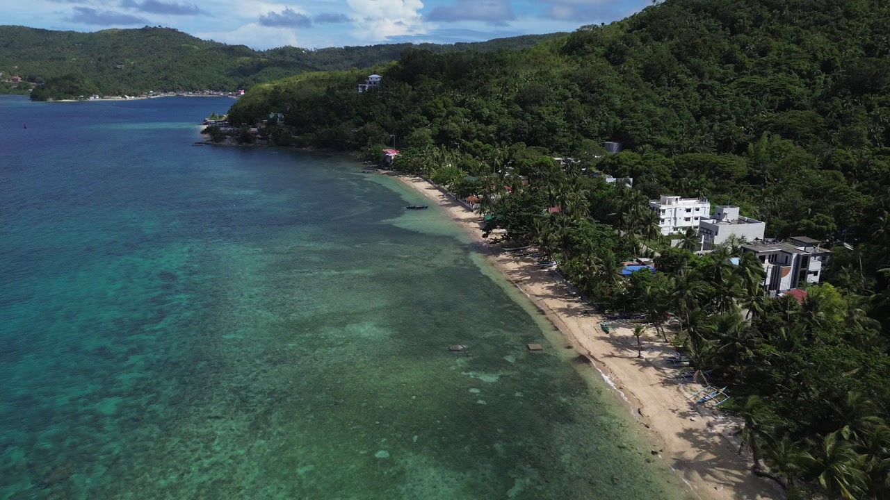 Aerial drone of Romblon coastline with crystal-clear turquoise water, green forested hills, and blue sky, showcasing tropical scenery, scenic landscapes, and exotic island views in the Philippines.