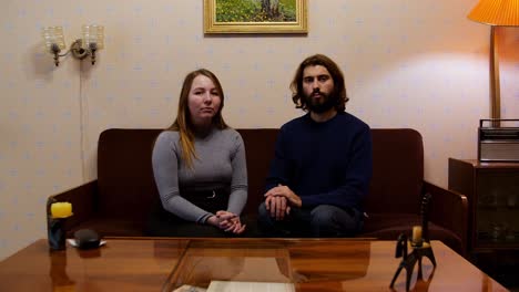 couple sitting on sofa in retro living room