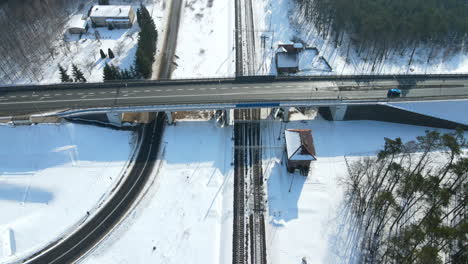 car drives in the flyover bridge surrounded by green forest and houses in snowy field in rakowice, krakow, poland