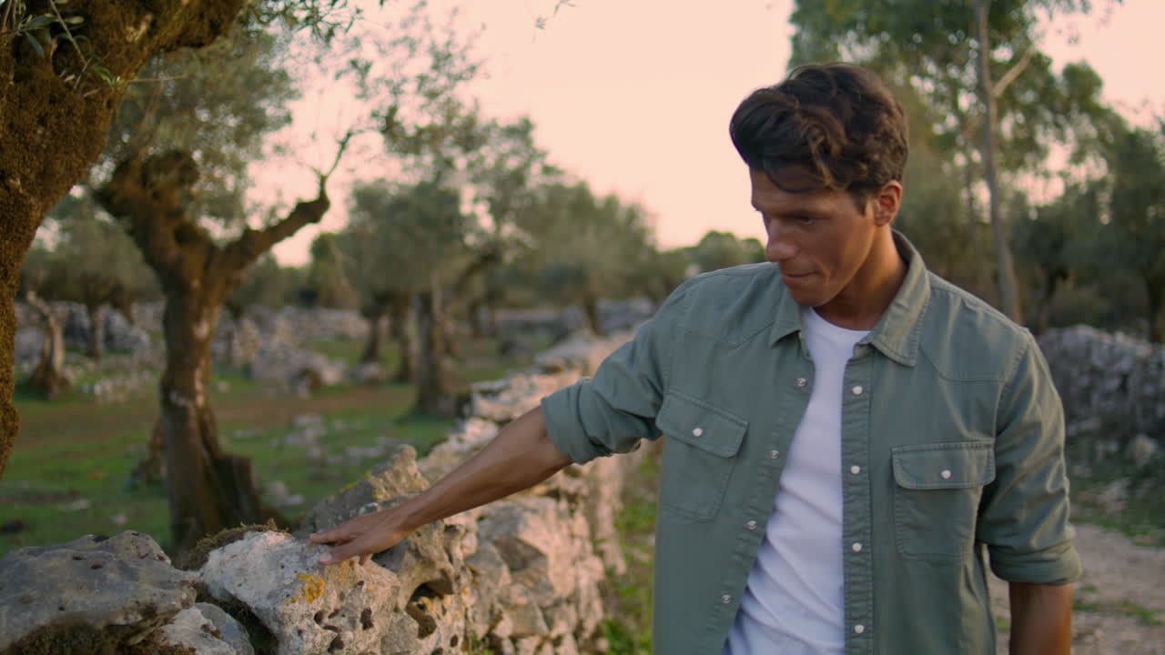 정원 초상화에서 돌 벽을 만지는 사려 깊은 남자. 혼자 는 편안한 남자