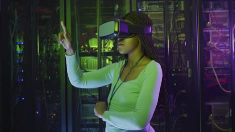 técnica informática afroamericana que usa auriculares vr trabajando en la sala de servidores de negocios
