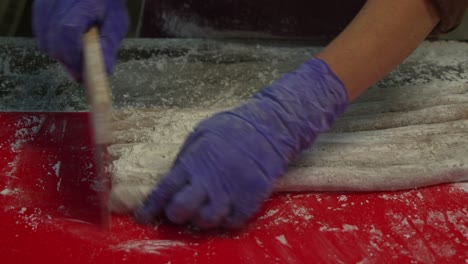 Hand-rolling-the-taro-dough-into-cylindrical-shapes,-chop-them-into-small-portions-using-a-dough-cutter,-close-up-shot-preparation-of-yam-balls,-the-popular-traditional-Taiwanese-dessert