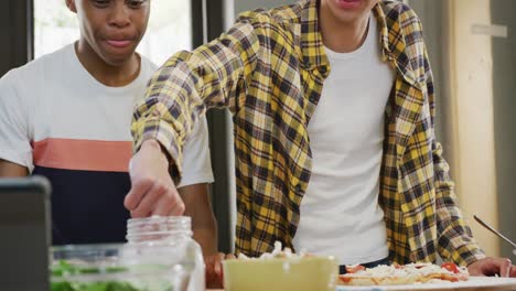 Happy-diverse-male-teenage-friends-preparing-pizza-in-kitchen,-slow-motion