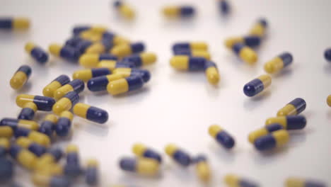 macro of blue and yellow pills dropped onto white background