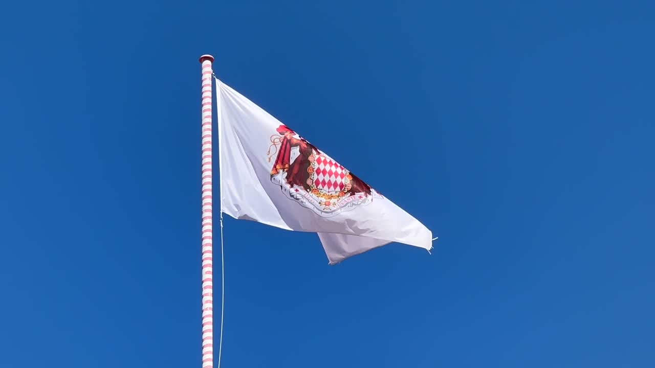 Waving Flag of Monaco against blue sky in sunlight. Close up slow motion shot. principality of Monaco,France.