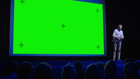 business conference stage: keynote speaker presents new product to the audience, movie theater shows green screen, mock-up, chroma key. live event on health and technology development topics