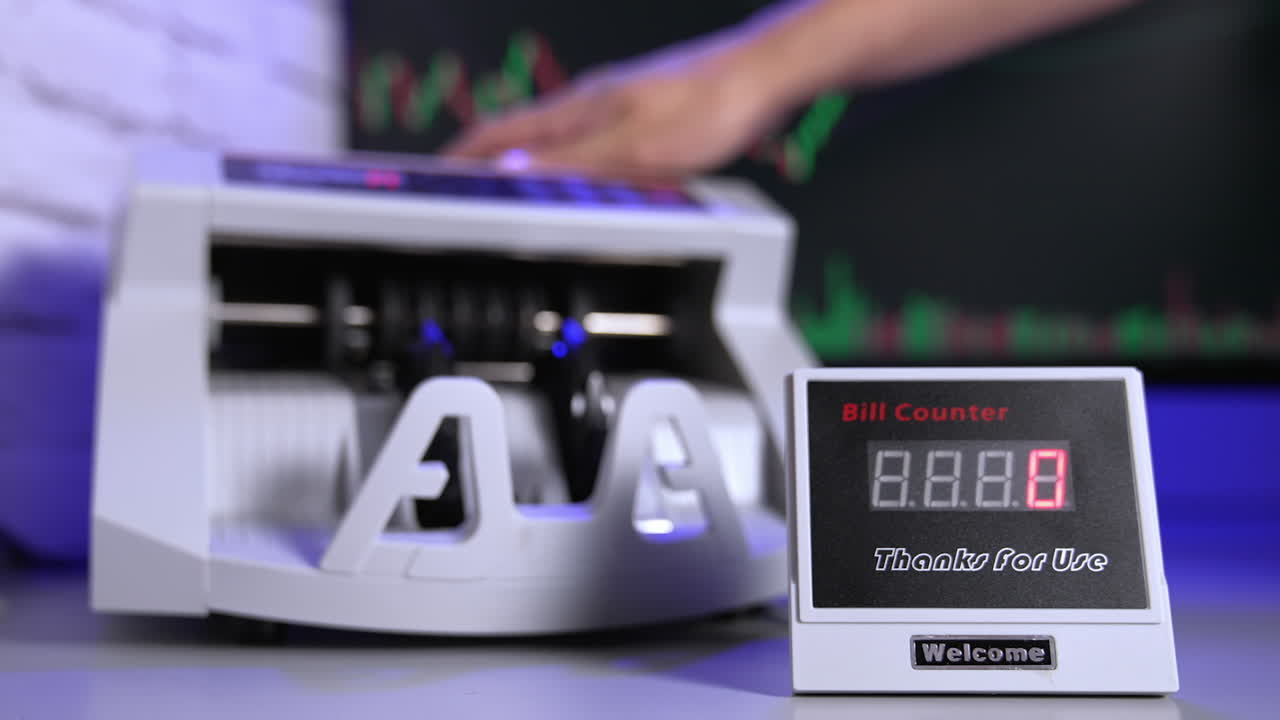 Modern cash counter machine on the table. Hand is putting a large amount of paper money into electronic machine for counting operation.